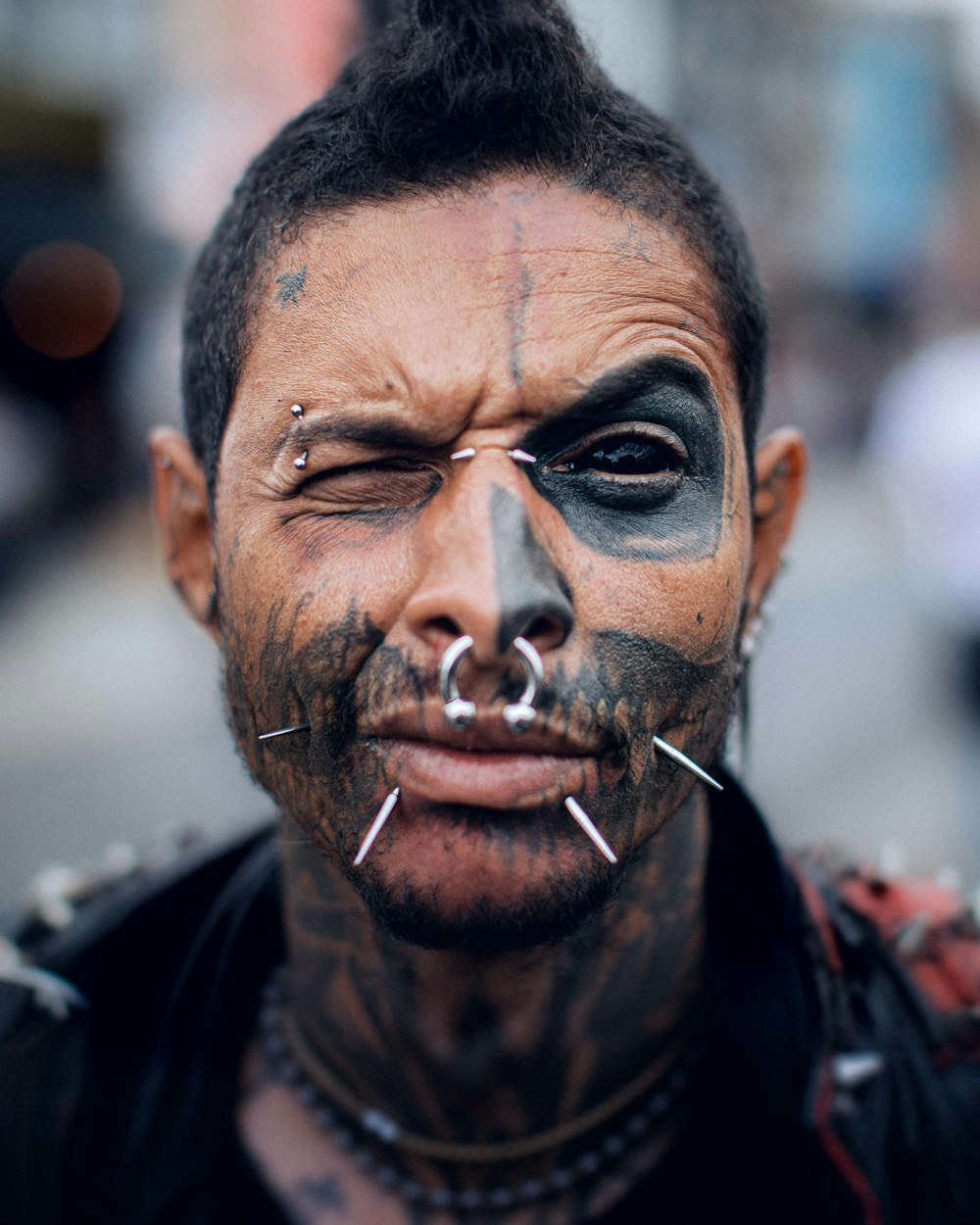 a man with black face paint and piercings on his nose