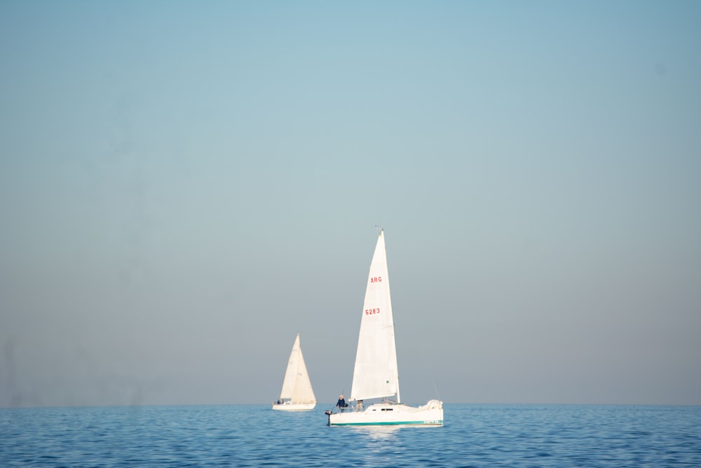 a couple of sailboats floating on top of a large body of water