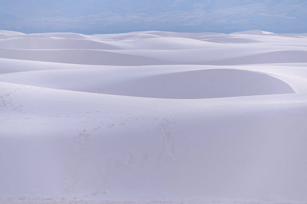 a group of white sand dunes under a blue sky