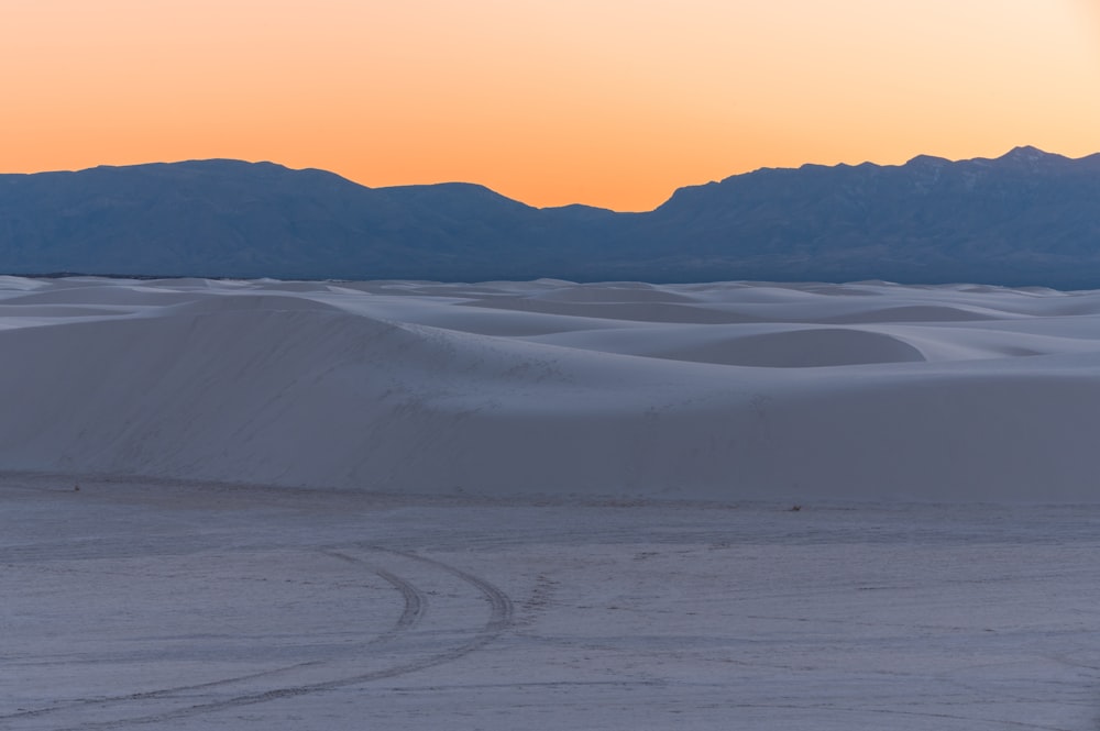 the sun is setting over the sand dunes