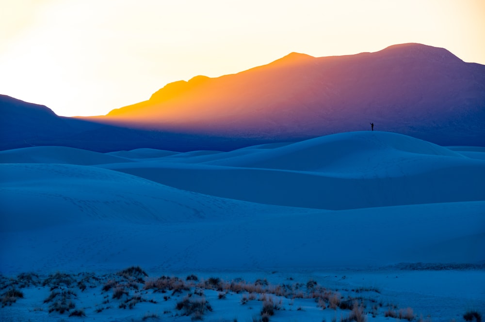 the sun is setting over the mountains in the desert