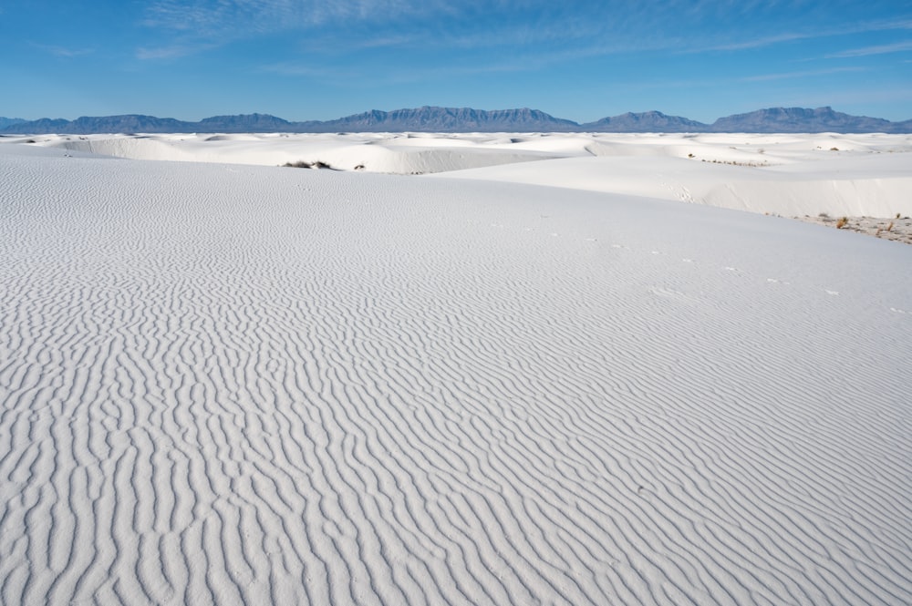 a wide expanse of white sand with mountains in the background