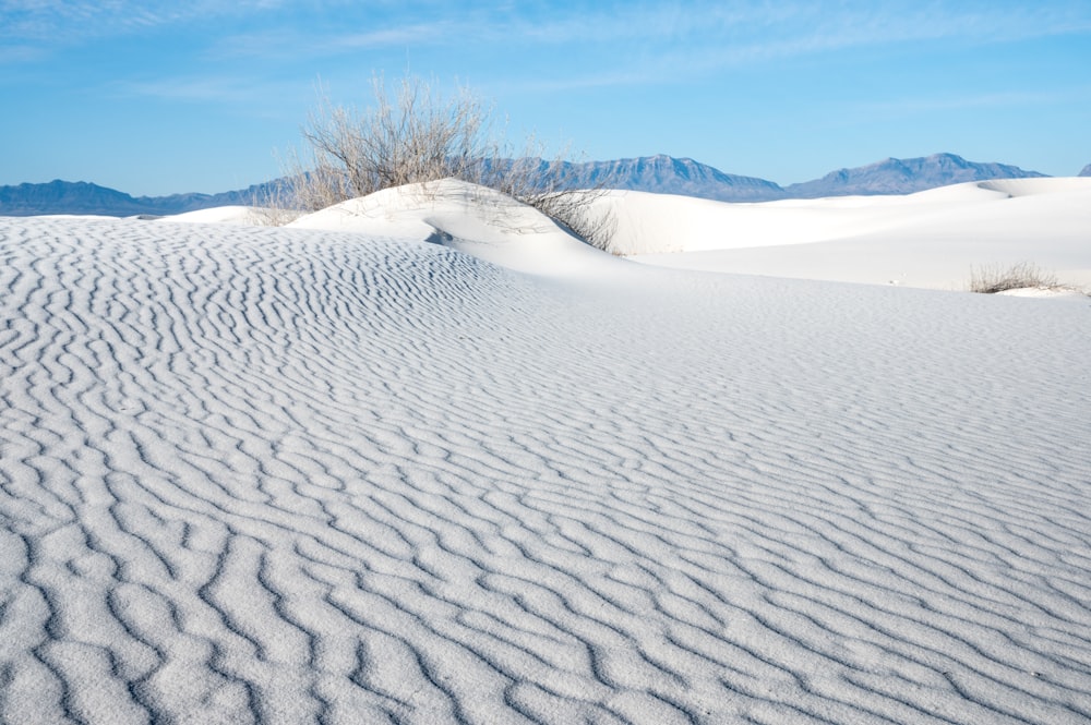 a large expanse of white sand with mountains in the background