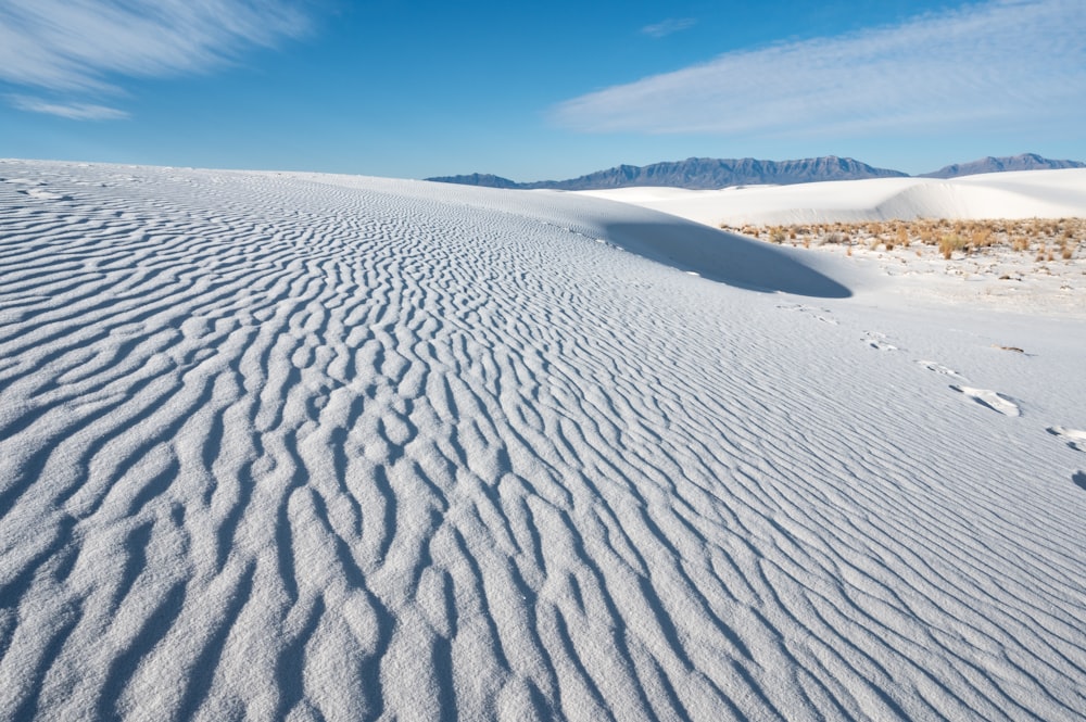 a wide expanse of white sand with mountains in the background