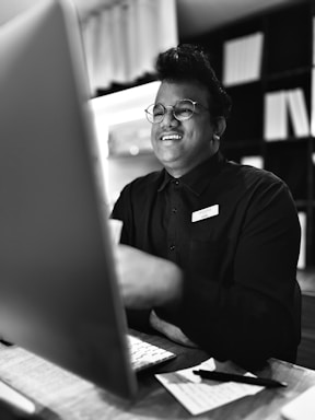 A friendly person sitting at a desk with a laptop and physics books, ready to respond to messages.