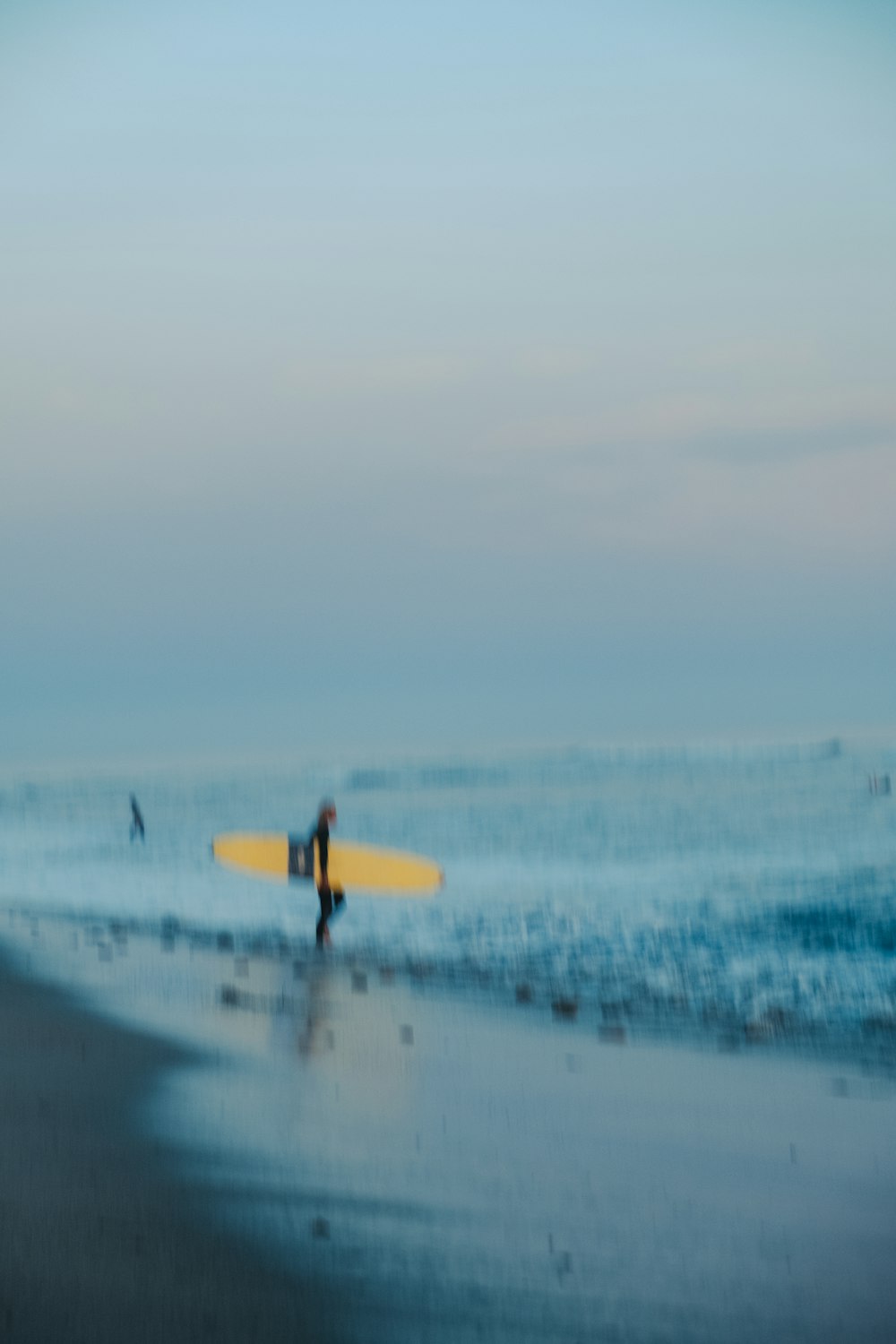 a blurry photo of a person carrying a surfboard