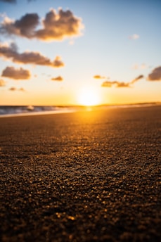 A serene beach scene at sunset with deep blue sea and soft golden light.