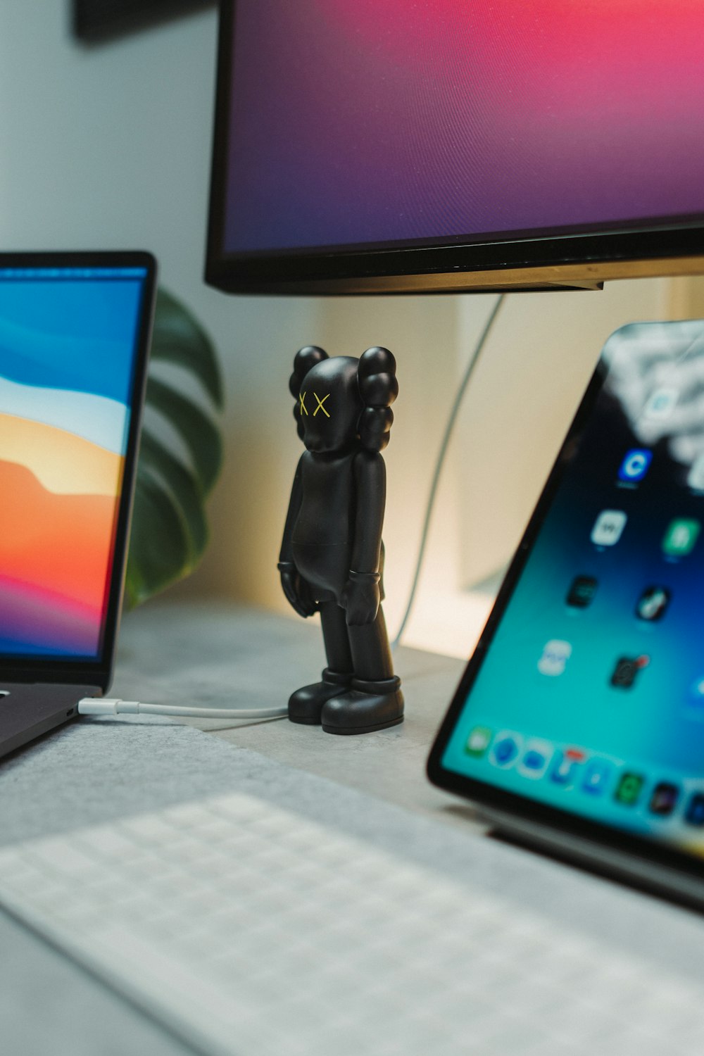 Une figurine d’ours noir assise sur un bureau à côté d’un ordinateur portable