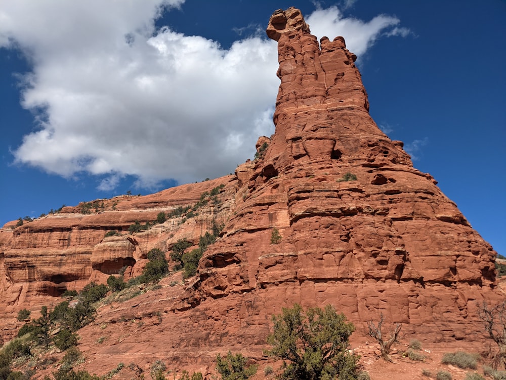 a tall red rock formation with a sky background