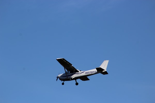 A small single-engine aircraft with a visible registration number flies against a clear blue sky.