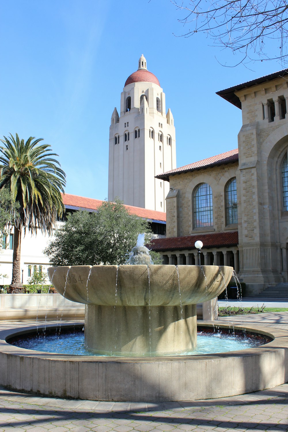 a fountain in front of a building with a clock tower in the background