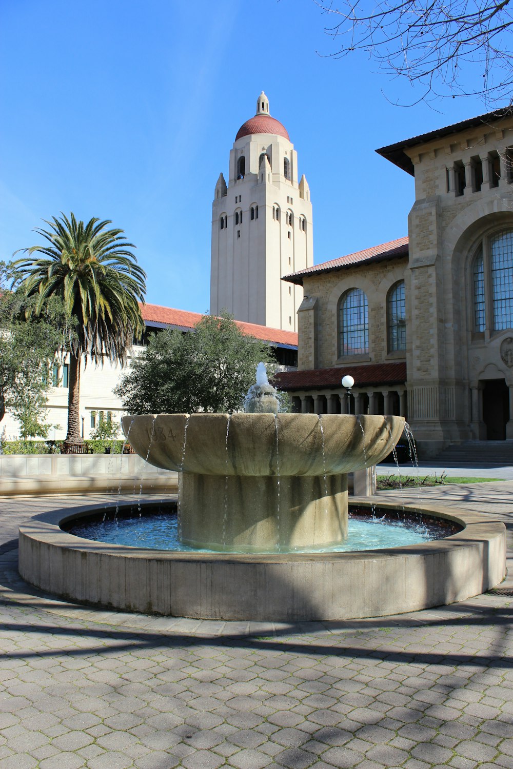 a fountain in front of a building with a clock tower in the background