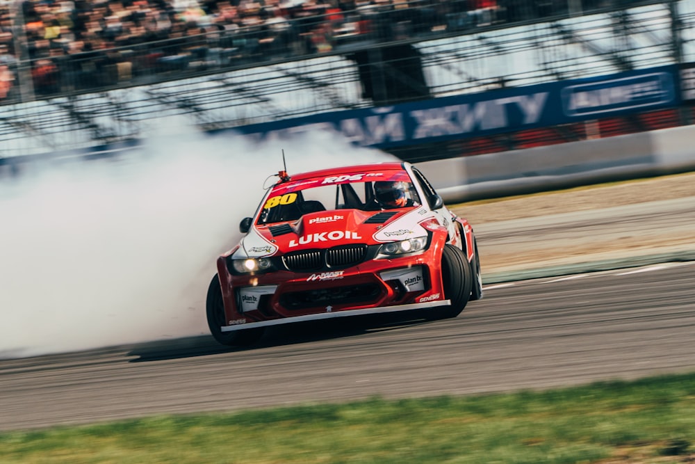 a red car driving down a race track with a lot of smoke coming out of