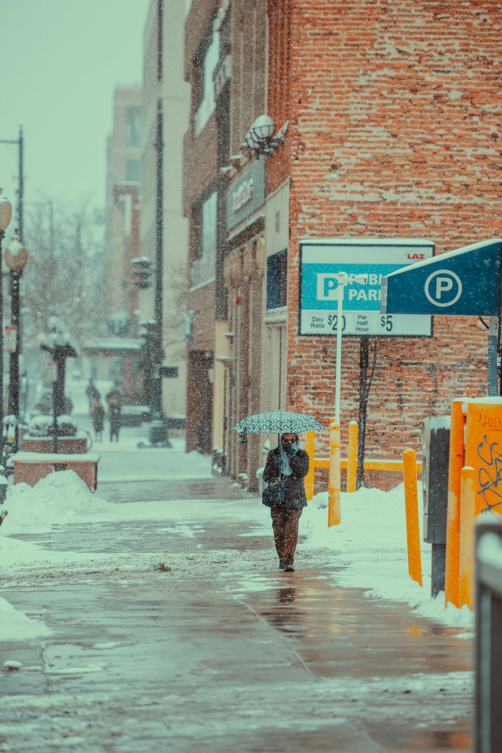 a person walking down a snow covered street holding an umbrella