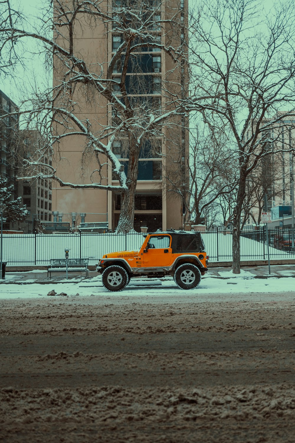 a yellow jeep parked in front of a tall building