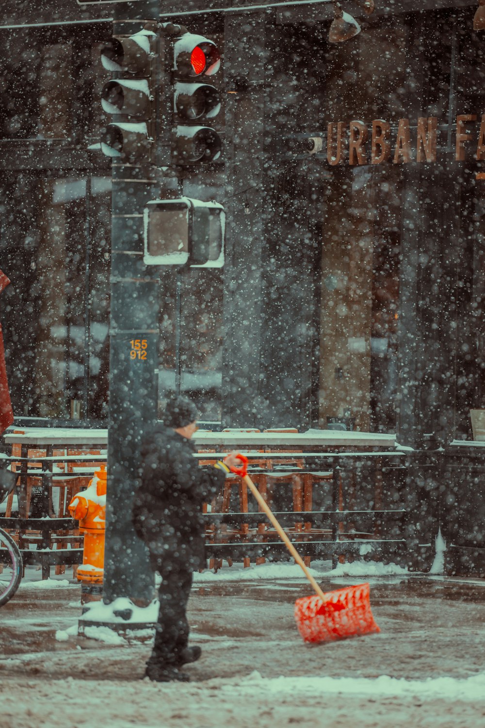 a man sweeping the snow off of a street