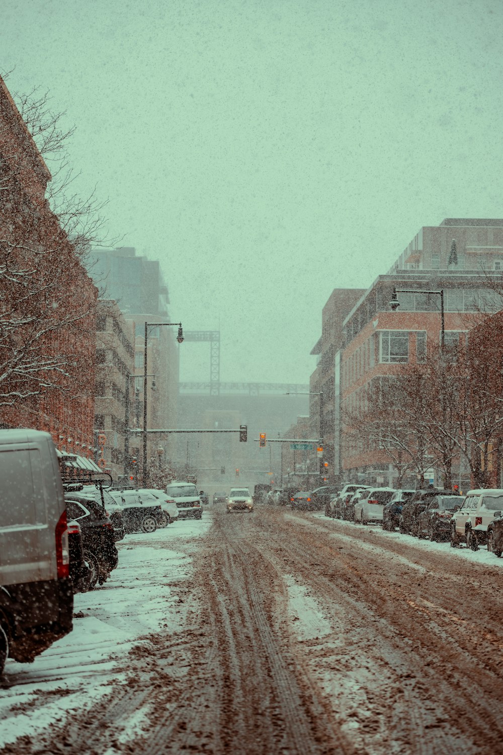 a snowy street with cars parked on the side of it