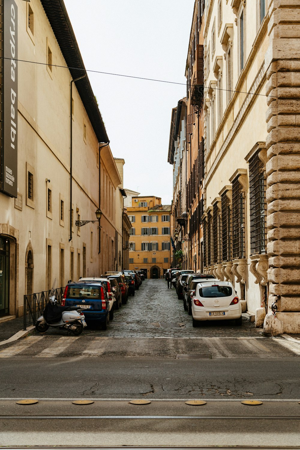 a row of parked cars on a street next to tall buildings