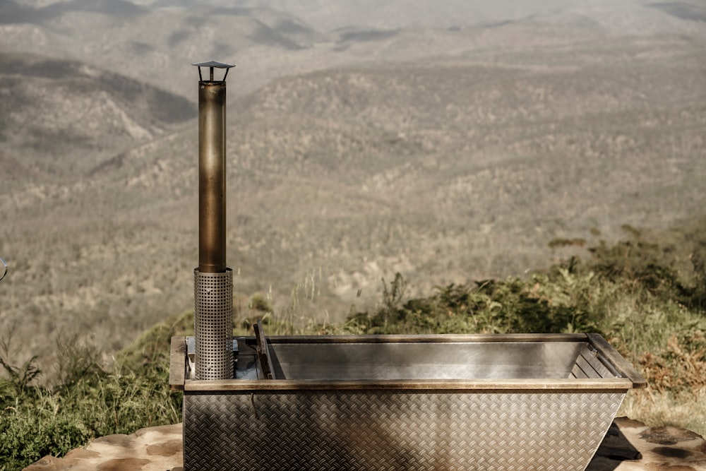 a large metal tub sitting on top of a lush green hillside