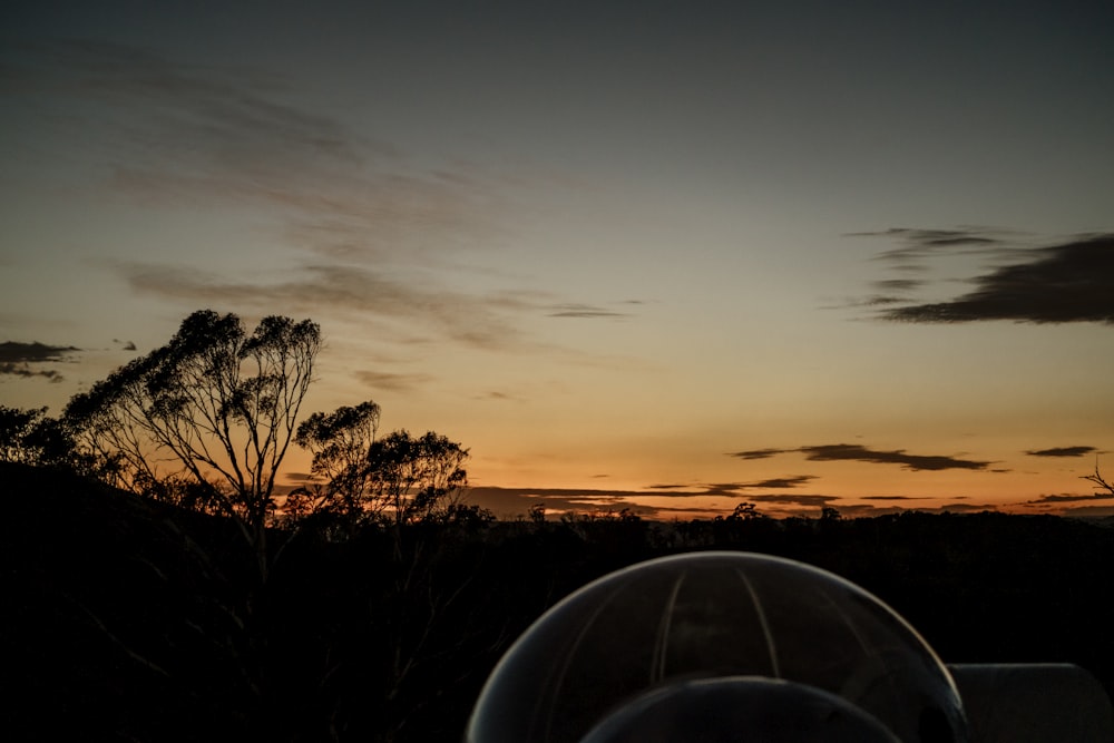 the sun is setting over the trees and hills