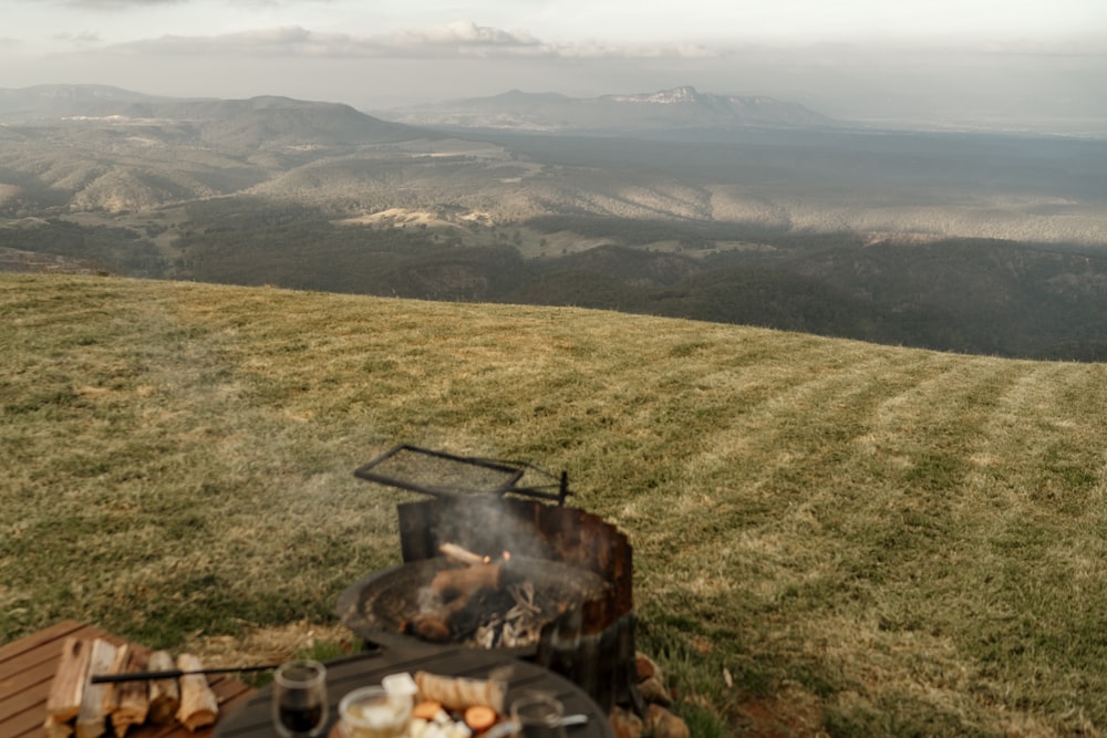 a table with a grill on top of a grass covered hill