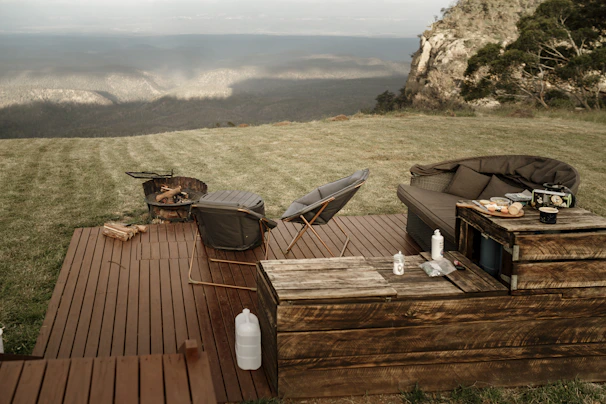Elegant outdoor living space featuring a stone fireplace and comfortable seating overlooking pine trees.