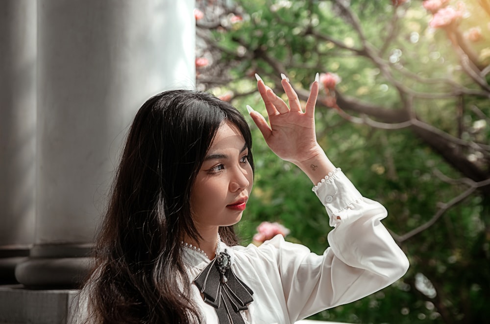 a woman in a white shirt is holding her hand up