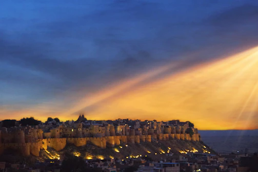 A vibrant photo of Jaipur's Amber Fort glowing at sunset with tourists exploring.