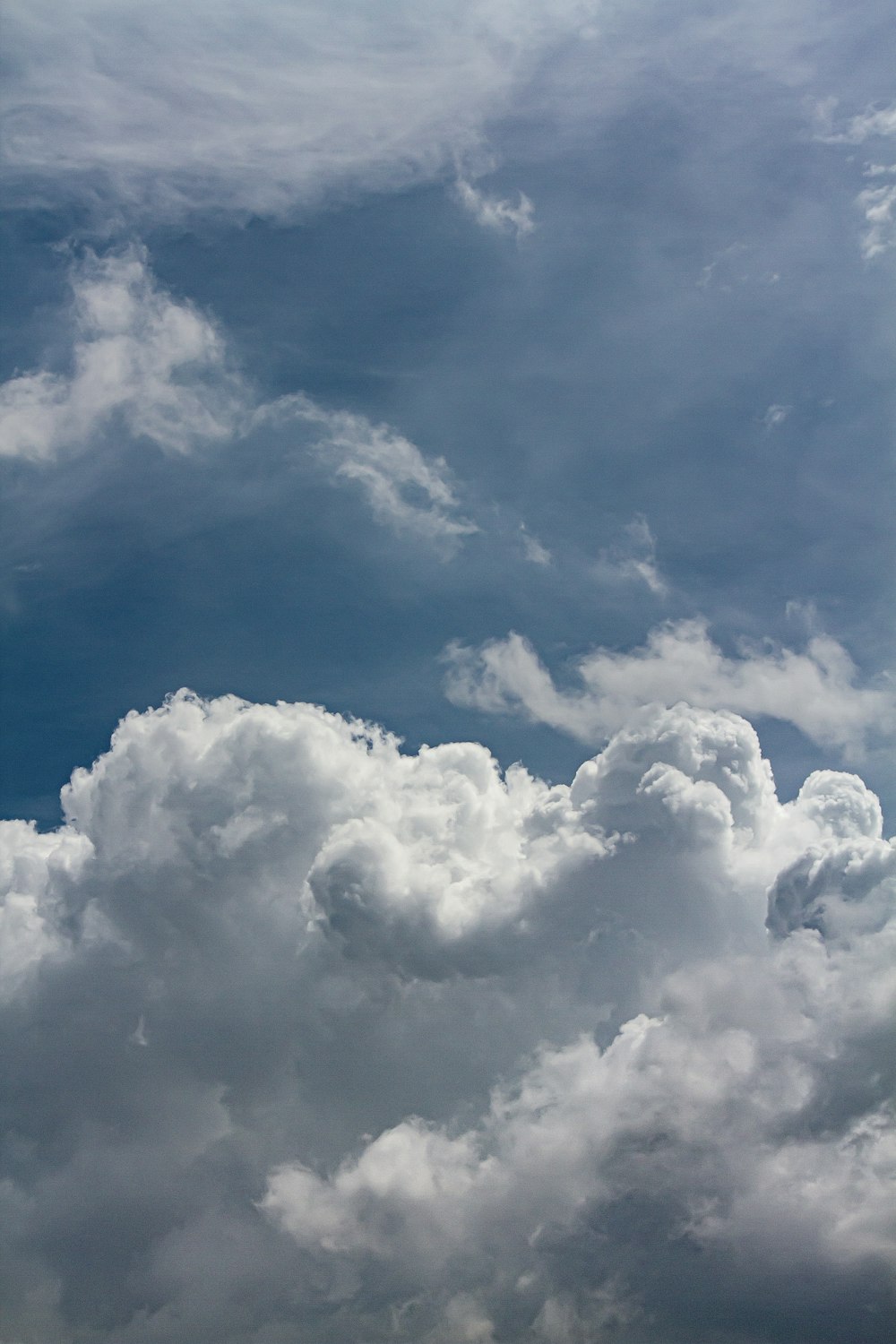 a plane flying through a cloudy blue sky