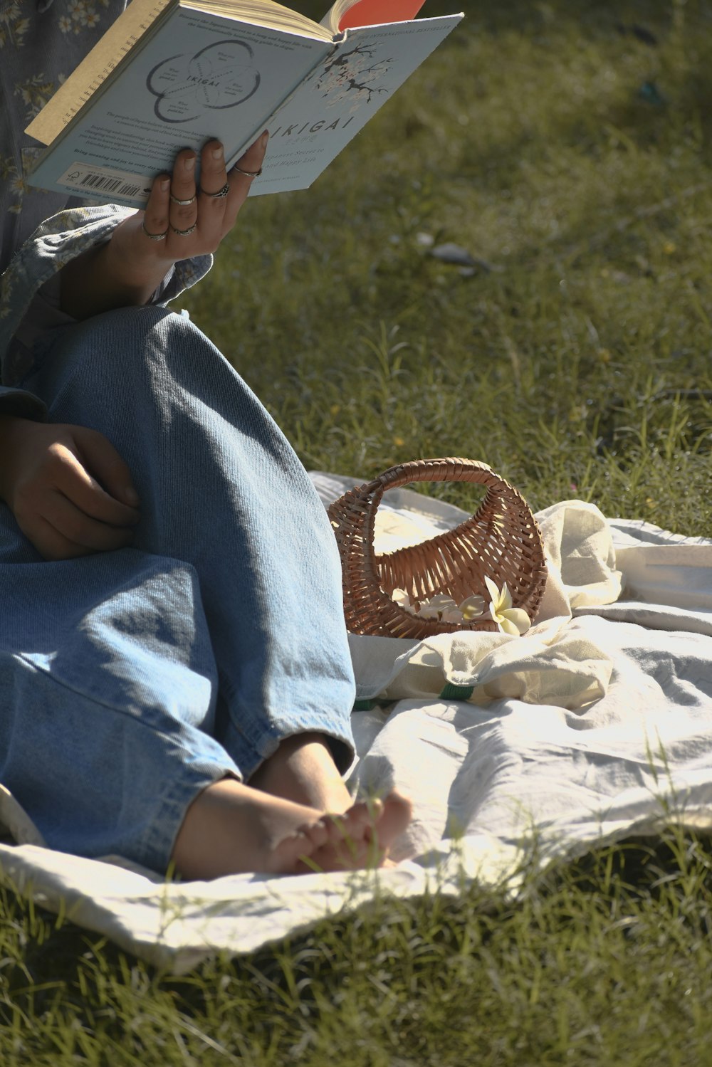 a person sitting on a blanket reading a book