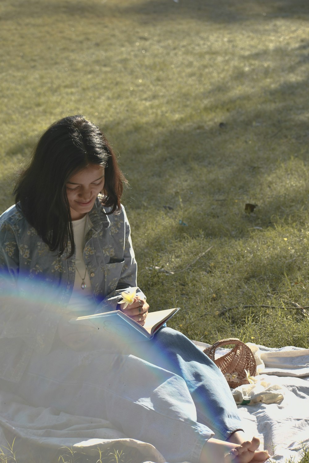 a woman sitting on a blanket in the grass