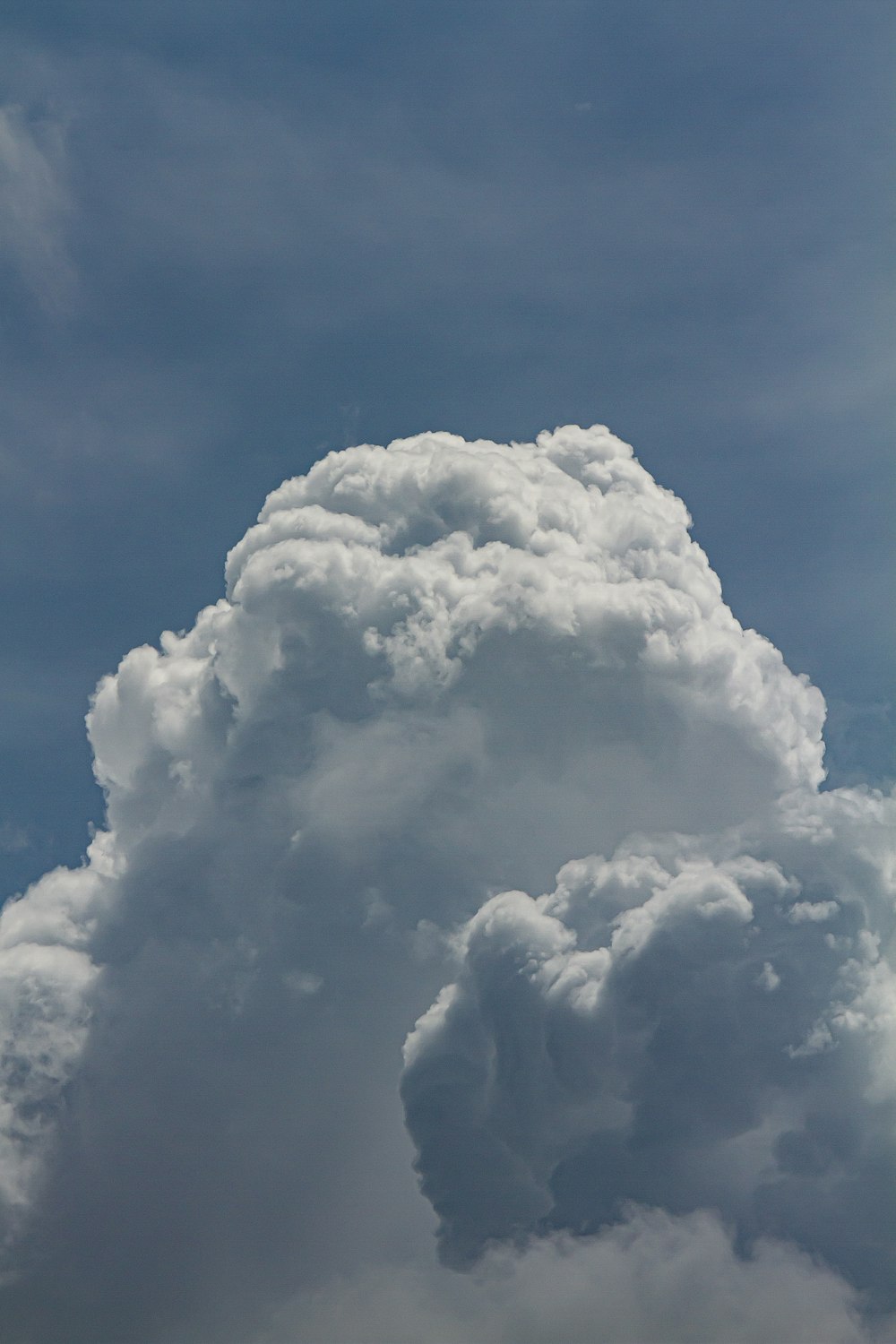 Eine große Wolke am Himmel mit einem vorbeifliegenden Flugzeug