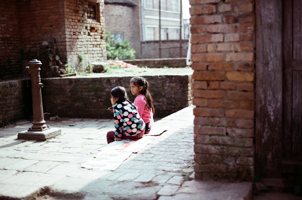Zwei kleine Mädchen sitzen nebeneinander auf dem Boden