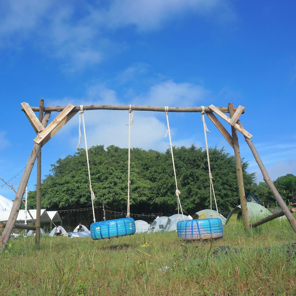 a wooden swing with two blue barrels on it