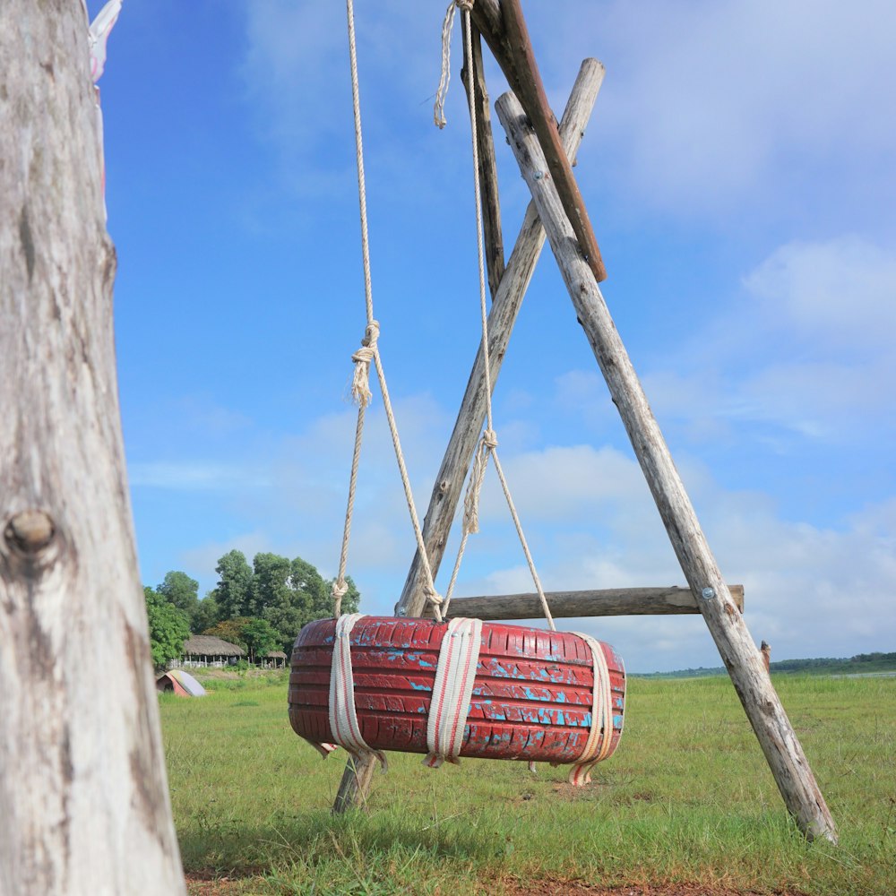 a wooden swing with a red barrel hanging from it