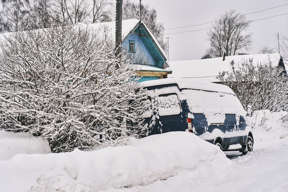 a car is covered in snow in front of a house