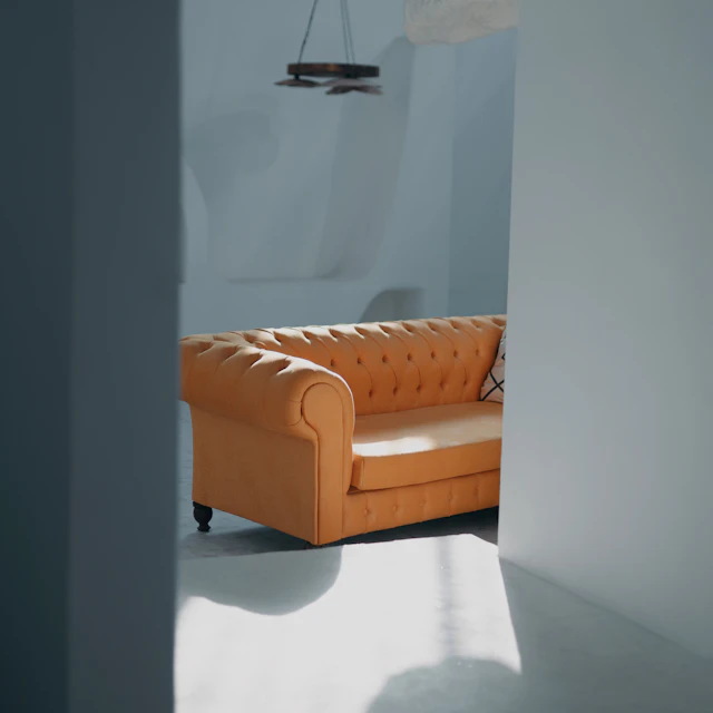 An orange couch sitting in a room next to a window
