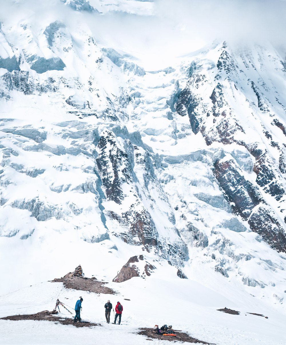 a group of people standing on top of a snow covered mountain