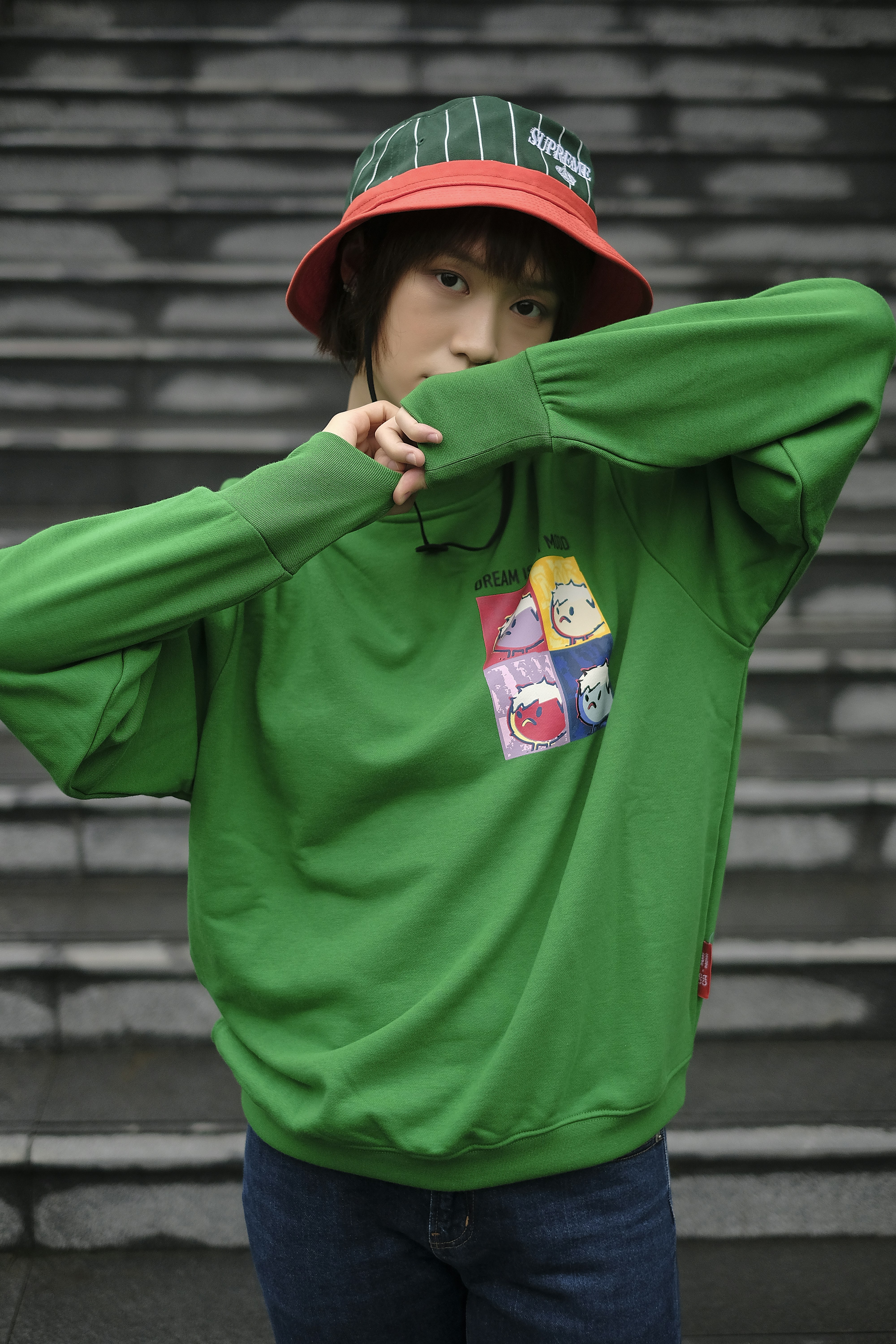 a young man wearing a green sweatshirt and a red hat