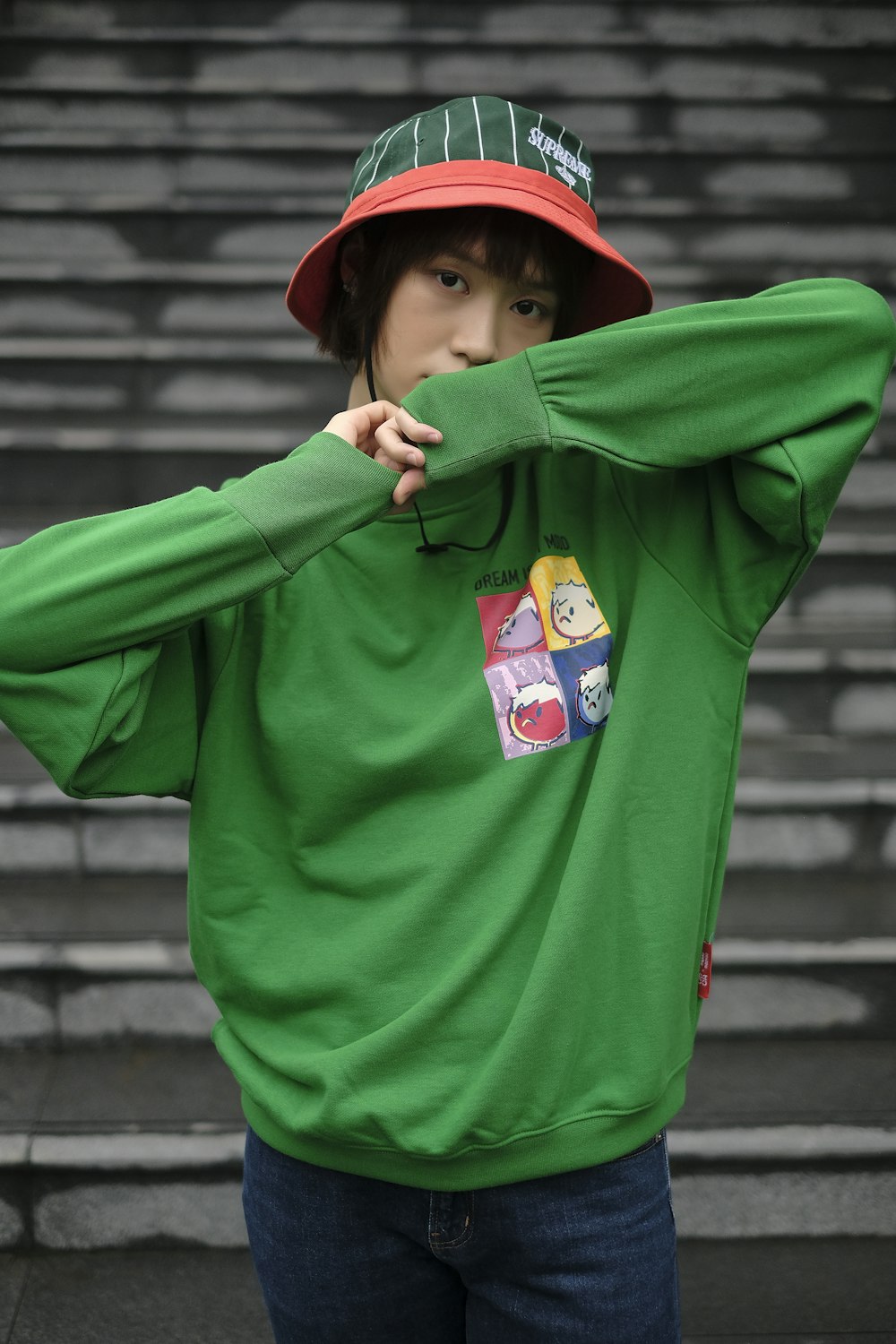 a young man wearing a green sweatshirt and a red hat