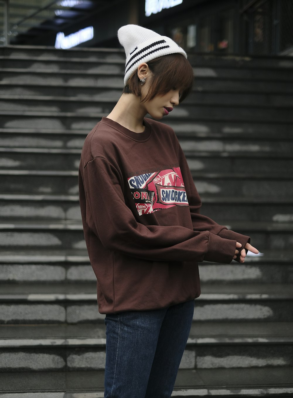 a woman standing in front of a set of stairs using a cell phone