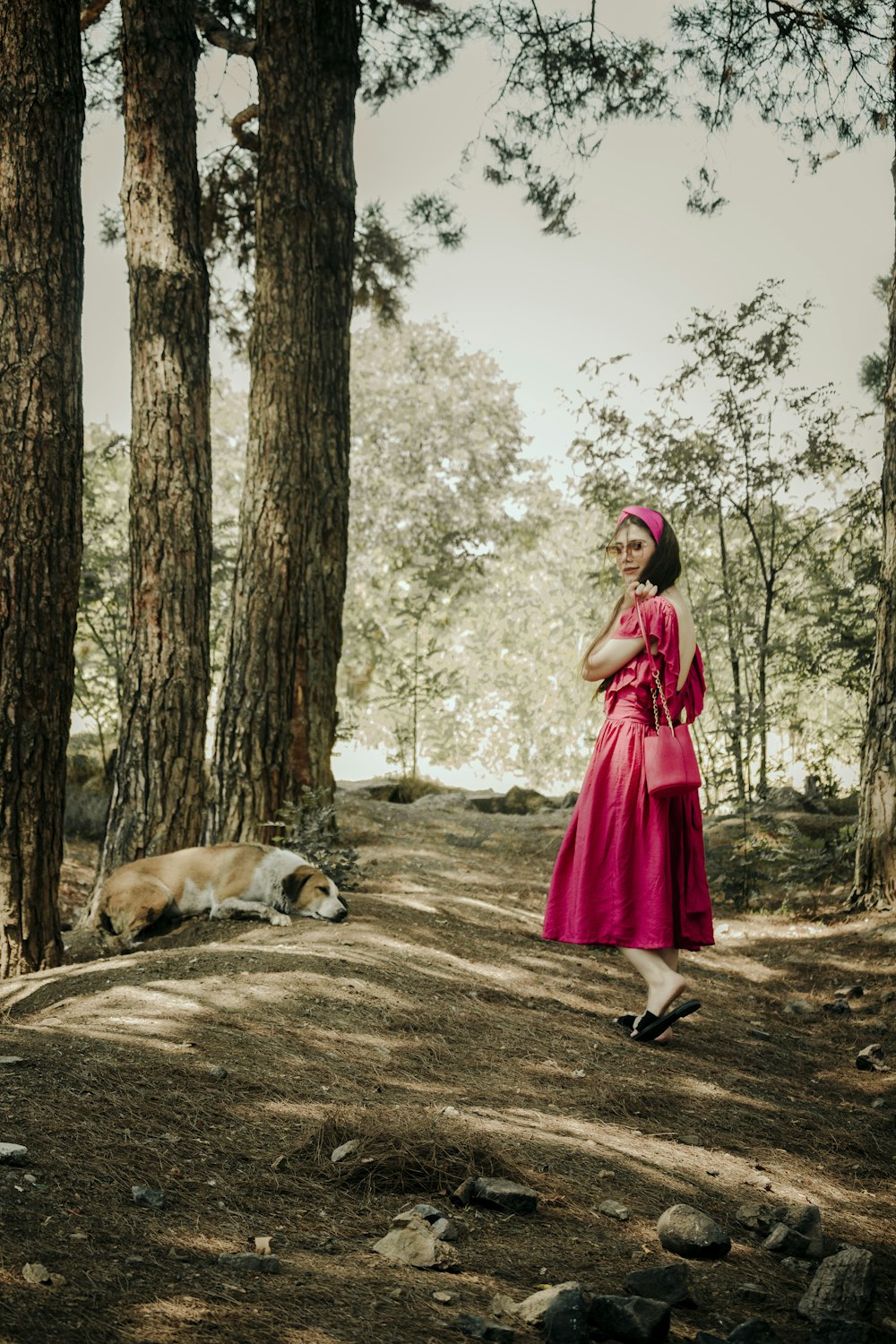 a woman in a pink dress standing in the woods