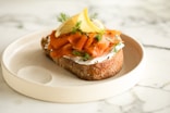 a piece of bread topped with carrots and a lemon wedge