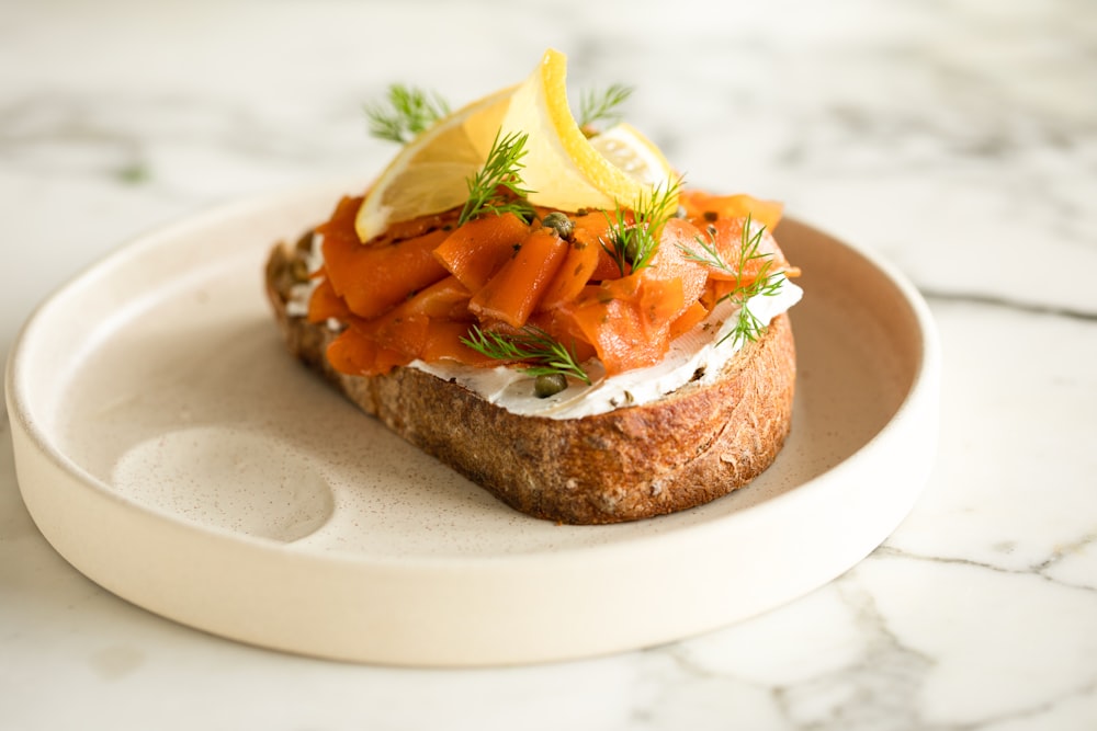 a piece of bread topped with carrots and a lemon wedge