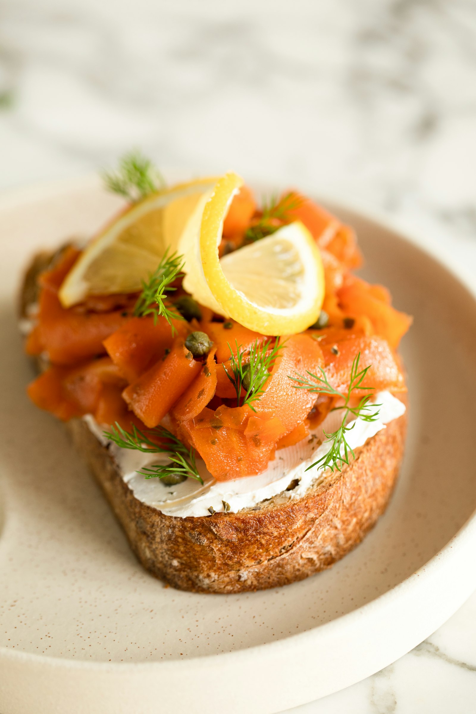 Gravet laks i Bergen servert i tynne skiver på grovt brød med dill, kapers og sitron