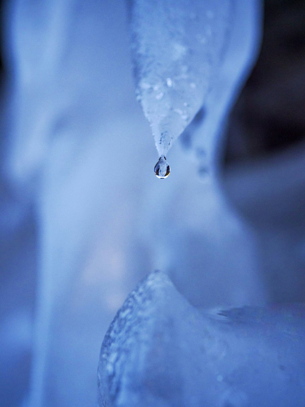 a drop of water that is hanging from a piece of ice