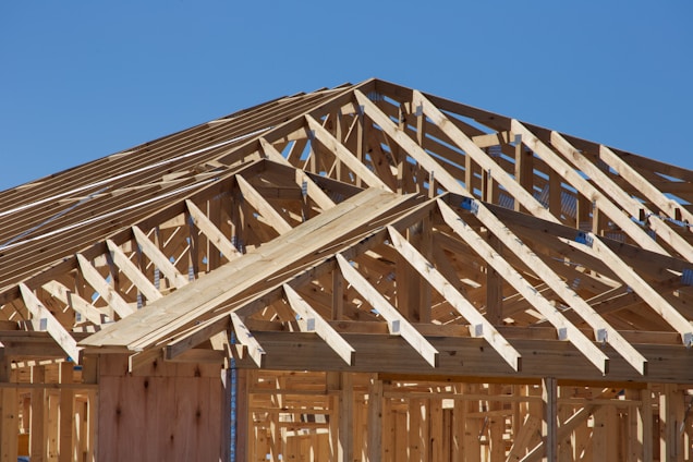 A skilled carpenter carefully framing a new deck under a bright blue sky.