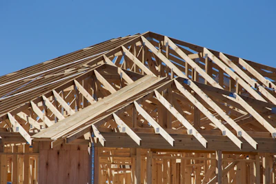 Close-up of precise framing work on a new pergola under a clear blue sky.
