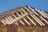 A detailed view of a wooden structure framework under construction, showcasing intersecting beams and trusses with a clear blue sky in the background.