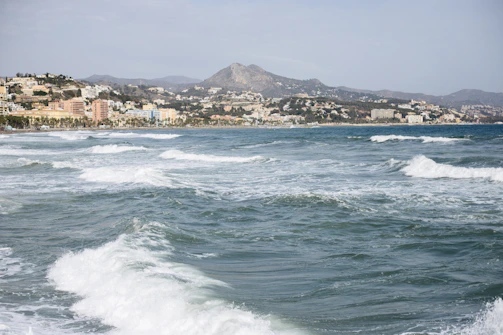 A calm coastal cityscape under a muted blue sky.